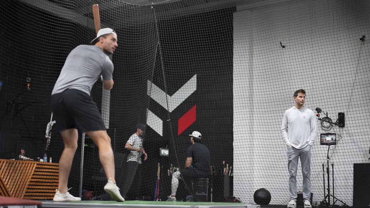 A hitter loads in the Maven capture cage while a coach watches from beside the monitoring station